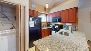 a kitchen with wooden cabinets and a black refrigerator at Woods Village 33 in Killington