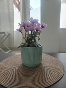 eine grüne Vase mit lila Blumen auf einem Tisch in der Unterkunft Departamento Acogedor Céntrico en Huanchaco3B in Huanchaco