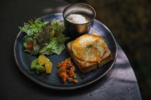 a plate with a sandwich and a salad and a drink at Villa SACHIIBARU 浜辺の茶屋 の 宿 in Nanjo