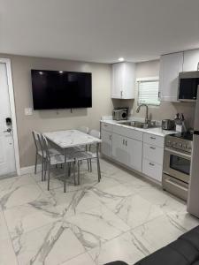 una cocina con una mesa con sillas y un televisor en Peace and Tranquility awaits, en Miami Gardens