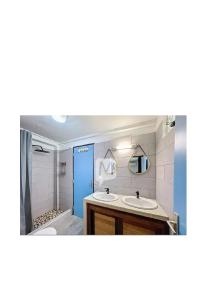 a bathroom with two sinks and a blue door at La mélodieuse in Macouria +2 photos