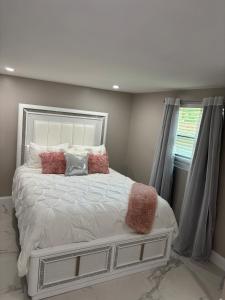Un dormitorio con una cama blanca con almohadas y una ventana. en Peace and Tranquility awaits, en Miami Gardens 5 fotos más