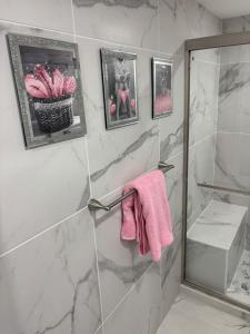 y baño con ducha y toalla rosa. en Peace and Tranquility awaits, en Miami Gardens