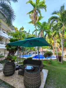 a patio with an umbrella and chairs and a pool at Alona Northland Resort in Panglao Island
