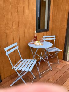 einen Tisch mit 2 Stühlen und einen Tisch mit einem Getränk in der Unterkunft Seascape on Maude in Oamaru