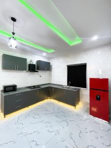 eine Küche mit einem roten Kühlschrank und einem Flachbildfernseher in der Unterkunft Luxurious 2bedroom Apartment PS5 in Ibadan