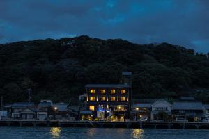 een gebouw op het water met een berg op de achtergrond bij 中尾甚六hotel in Karatsu
