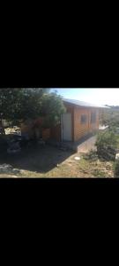 een huis met een garage en een boom ervoor bij Cabaña Flor Serrana in Tanti