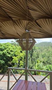 a straw umbrella on a deck with a view of trees at Zen Garden Palace in Ella