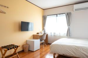 une chambre avec un lit, un bureau et une télévision dans l'établissement 蔵の宿, à Kamogawa
