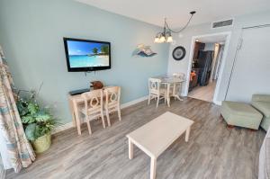 a living room with a table and a tv on the wall at Condo near Barefoot Landing w beach access in Myrtle Beach