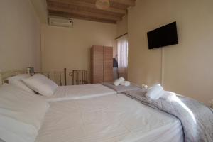 a bedroom with a large white bed with a flat screen tv at Elia Studio in Sokrákion