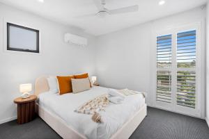 a white bedroom with a bed and a window at Seabreeze in Kingscliff +16 photos