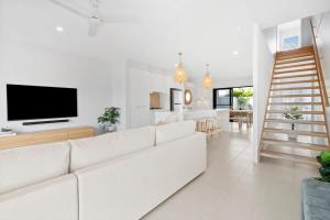 a white living room with a white couch and a television at Seabreeze in Kingscliff