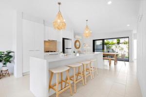 a white kitchen with a large island with bar stools at Seabreeze in Kingscliff