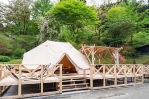 a tent on a wooden platform with trees in the background at ザランタン鹿沼 in Kanuma