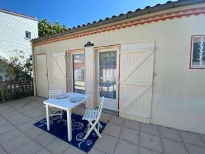 une table blanche et deux chaises devant un garage dans l'établissement Petite maison calme proche centre et plages - FR-1-709-76, à Fouras