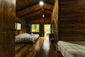 une chambre avec deux lits dans une cabane en rondins dans l'établissement Hotel Pedacito de Cielo, à Boca Tapada