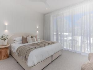 a white bedroom with a bed and a large window at Kai Residences in Cabarita Beach