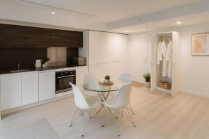 a kitchen with a glass table and white chairs at Chic City Living 2-Bedroom Condo in the Best Downtown Spot in Vancouver