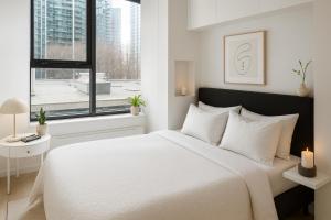 a white bedroom with a large bed and a window at Chic City Living 2-Bedroom Condo in the Best Downtown Spot in Vancouver