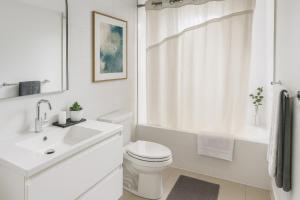 a white bathroom with a toilet and a sink at Chic City Living 2-Bedroom Condo in the Best Downtown Spot in Vancouver
