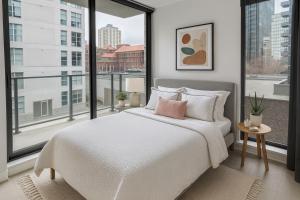 a bedroom with a white bed and a large window at Chic City Living 2-Bedroom Condo in the Best Downtown Spot in Vancouver