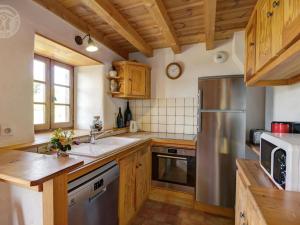 une cuisine avec des armoires en bois et un réfrigérateur en acier inoxydable dans l'établissement Gîte cosy avec jardin clos et animaux acceptés - FR-1-496-119, à Virigneux 10 autres photos