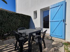 une table avec deux chaises et une porte bleue dans l'établissement Maisonnette conviviale proche plage pour 4 pers. - FR-1-476-174, à La Faute-sur-Mer