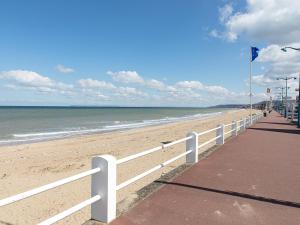 einen Strand mit einem weißen Zaun und dem Meer in der Unterkunft Studio rénové au cœur de Villers-sur-Mer, proche plage et commerces - FR-1-712-61 in Villers-sur-Mer + 6 Fotos