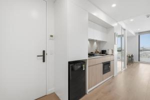 a kitchen with white walls and a black refrigerator at Coastal Apartment with Rooftop Pool in North Fremantle