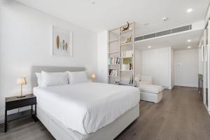 a white bedroom with a large bed and a book shelf at Coastal Apartment with Rooftop Pool in North Fremantle