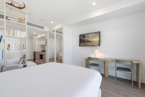 a white bedroom with a white bed and a desk at Coastal Apartment with Rooftop Pool in North Fremantle +27 photos