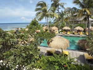 a resort with a swimming pool with chairs and umbrellas at Seven Dreams A Pramana Experience in Nusa Penida