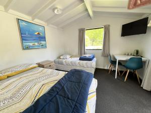 a room with two beds and a desk with a computer at Parklands Marina Holiday Park in Picton +69 photos