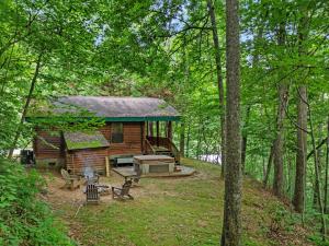 une cabane en rondins dans les bois avec un grill dans l'établissement Good Life Cabin 2, à Bryson City
