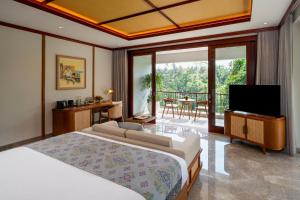 a bedroom with a bed and a television and a balcony at Adiwana Alas Harum in Ubud