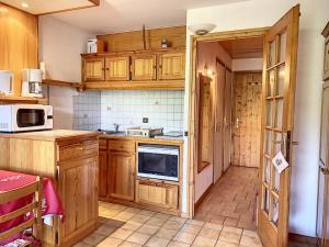 a kitchen with wooden cabinets and a microwave at Studio cosy pour 3 avec terrasse, parking et casier à ski à Combloux - FR-1-560-77 in Combloux