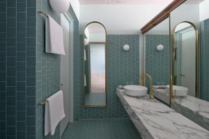 a bathroom with green tile and two sinks and mirrors at The Calile Hotel in Brisbane