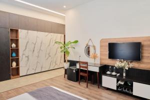 a living room with a tv and a table with a chair at Anchie Retreat Villa Hội An in An Bang +16 photos