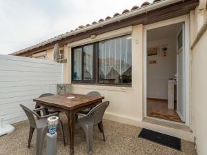 eine Terrasse mit einem Holztisch und Stühlen in der Unterkunft Appartement pour 3 à Mimizan Plage, à 50m de l'océan avec terrasse et parking, ménage inclus - FR-1-50-123 in Mimizan