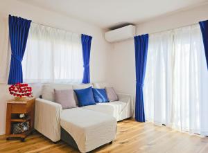 ein Wohnzimmer mit einem weißen Sofa und blauen Vorhängen in der Unterkunft 鎌倉江の島 腰越駅徒歩3分海まで5分 2025年新築貸切一戸建て in Kamakura