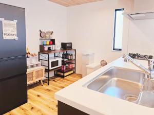 eine Küche mit einer Spüle und einem schwarzen Kühlschrank in der Unterkunft 鎌倉江の島 腰越駅徒歩3分海まで5分 2025年新築貸切一戸建て in Kamakura + 35 Fotos