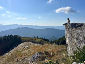 une personne assise au sommet d'un gros rocher sur une montagne dans l'établissement Kasamatsutei - Vacation STAY 73449v, à Shimizu 2 autres photos