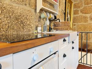 eine Küche mit weißen Schränken und einer Steinmauer in der Unterkunft Mansion in Vale Abrigoso - Mezio with Patio in Vale Abrigoso + 32 Fotos