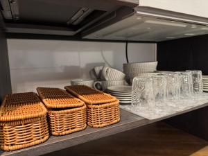 una estantería con cestas de mimbre, platos y vasos en 鶴岡市中心地ゲストハウス, en Tsuruoka 20 fotos más