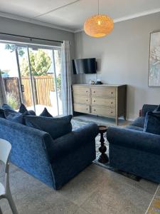 a living room with two blue couches and a television at Tree Aloe Guest house in St Francis Bay