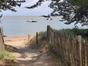 a boat in the water with a fence and a beach at Maisonnette à Barbâtre, proche plage, animaux admis, 2-4 pers. - FR-1-823-118 in Barbâtre