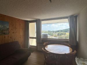 a living room with a table and a large window at Studio à Super Besse avec vue sur pistes et balcon - FR-1-814-16 in Besse-et-Saint-Anastaise