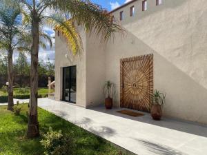 El Jemʼa GhematMagnifique Villa Proche Marrakech 4 Chambres, Piscine 10m, Accueille 8 à 10 Personnes的一栋有棕榈树和门的房子的入口